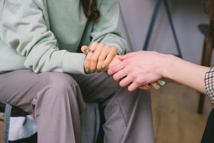 Two people comforting each other by touching hands.