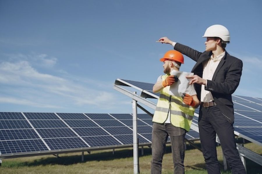 Two people in hard hats looking at solar panels.