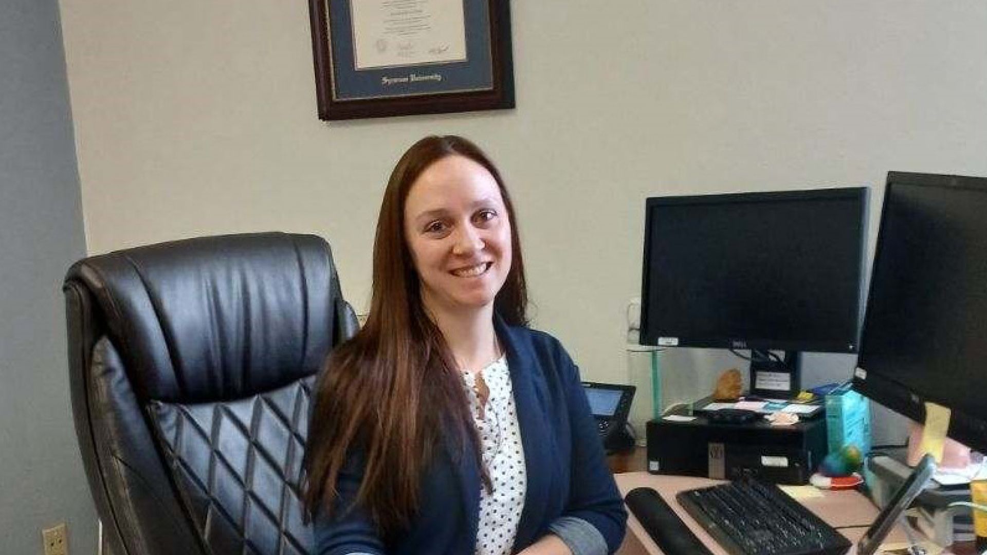 Patricia Schaap, Class of 2004 Patricia Schaap smiling and seated at a desk in an office.