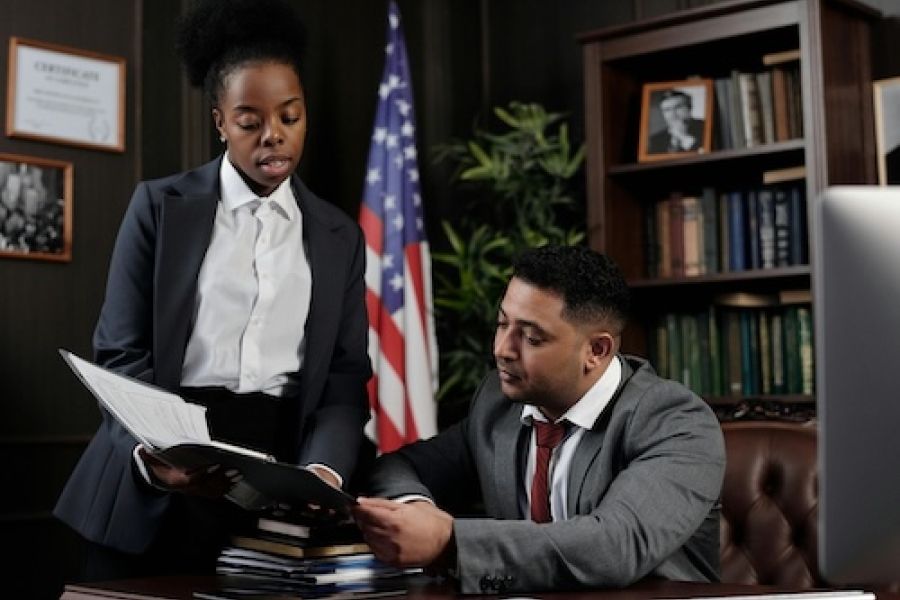 Two people in an office looking at paperwork. They are wearing suits.