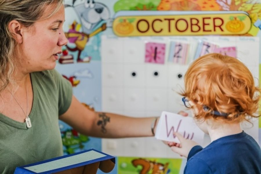 Preschool teacher working with a child.